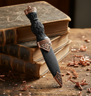 Decorative dagger with black handle and rose gold accents on a white background